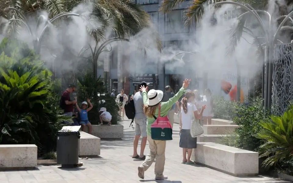 People using mist-based cooling infrastructure in a landscaped public space